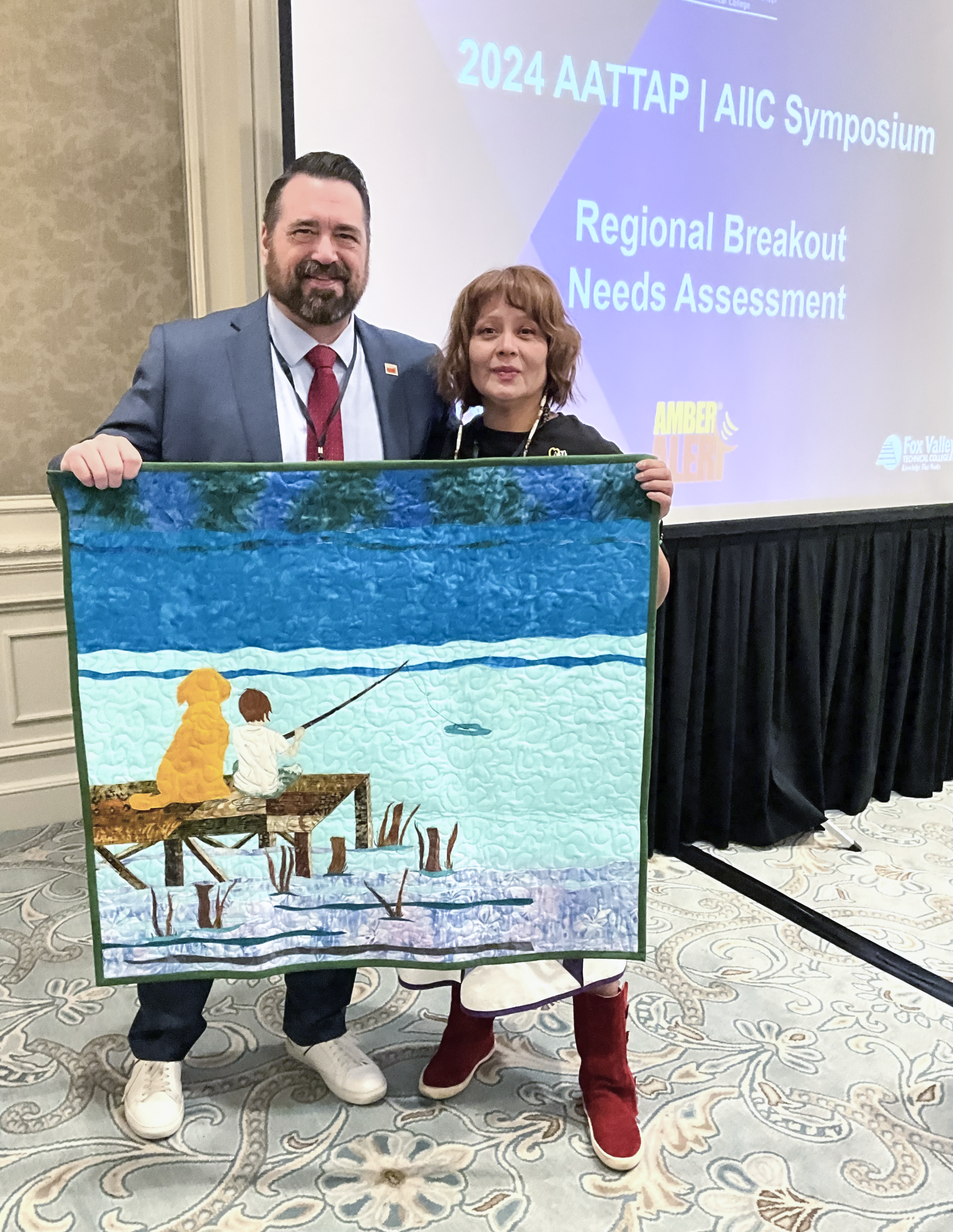 Image showing Derek VanLuchene and Pamela Foster holding a memorial quilt she made for him in tribute to his late brother and dog.